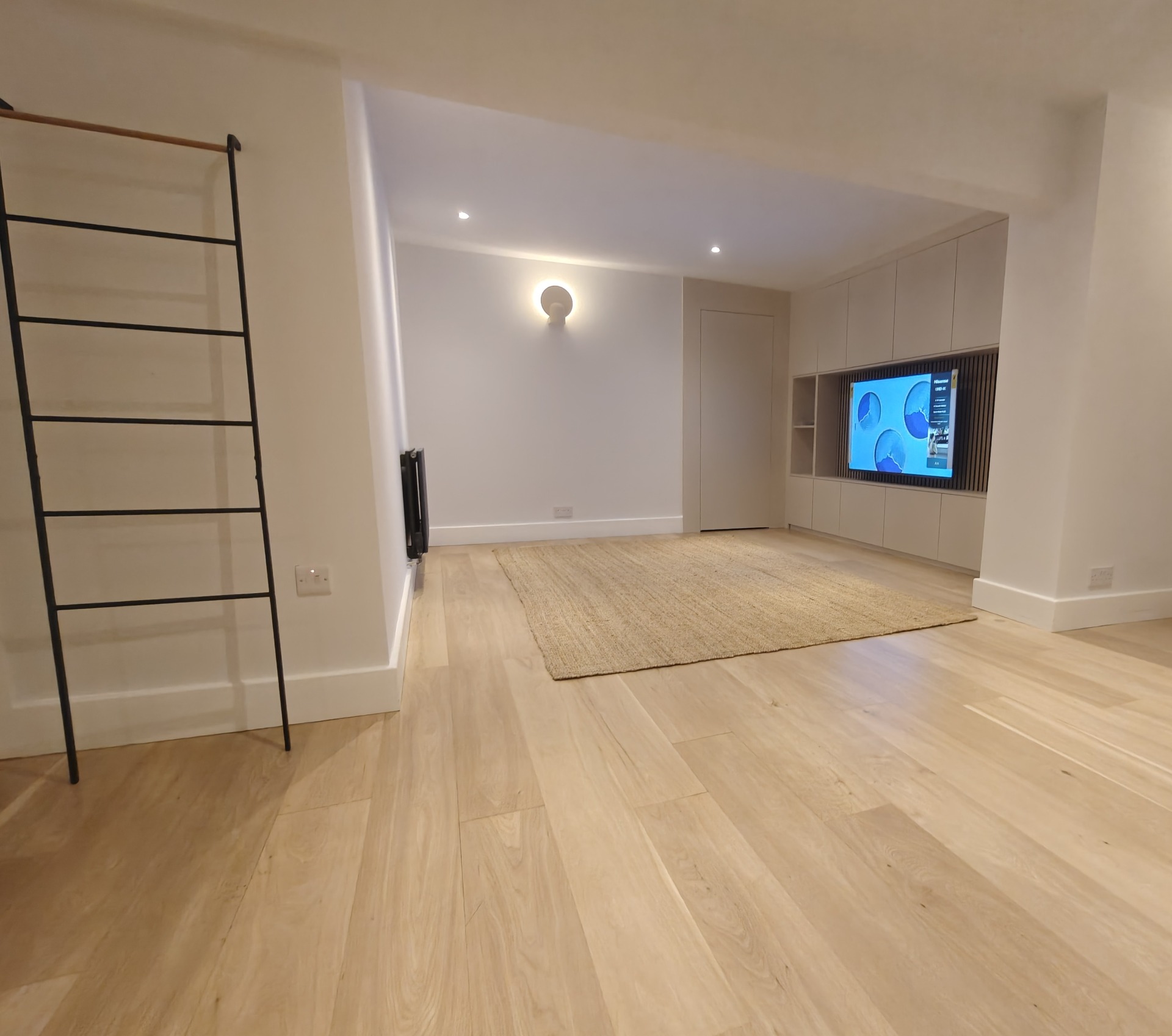 Open-plan living space with light oak flooring and media wall